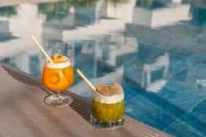 Two colorful cocktails with straws by the poolside, perfect for summer relaxation.