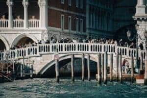 A crowded bridge over a canal in Venice, Italy, showcasing tourists and historic architecture.