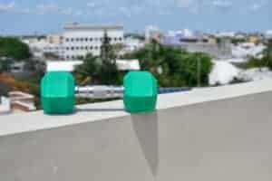 A green dumbbell resting on a rooftop ledge in Cancún with a city skyline view.