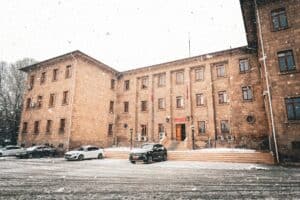 Snow-covered historic building with cars, showcasing winter ambiance.