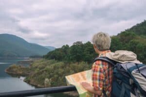 Traveler with backpack and map exploring picturesque mountain landscape.