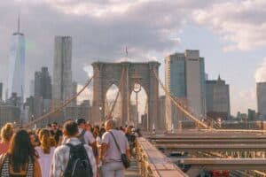A vibrant sunset view of the Brooklyn Bridge with people enjoying the iconic skyline of New York City.