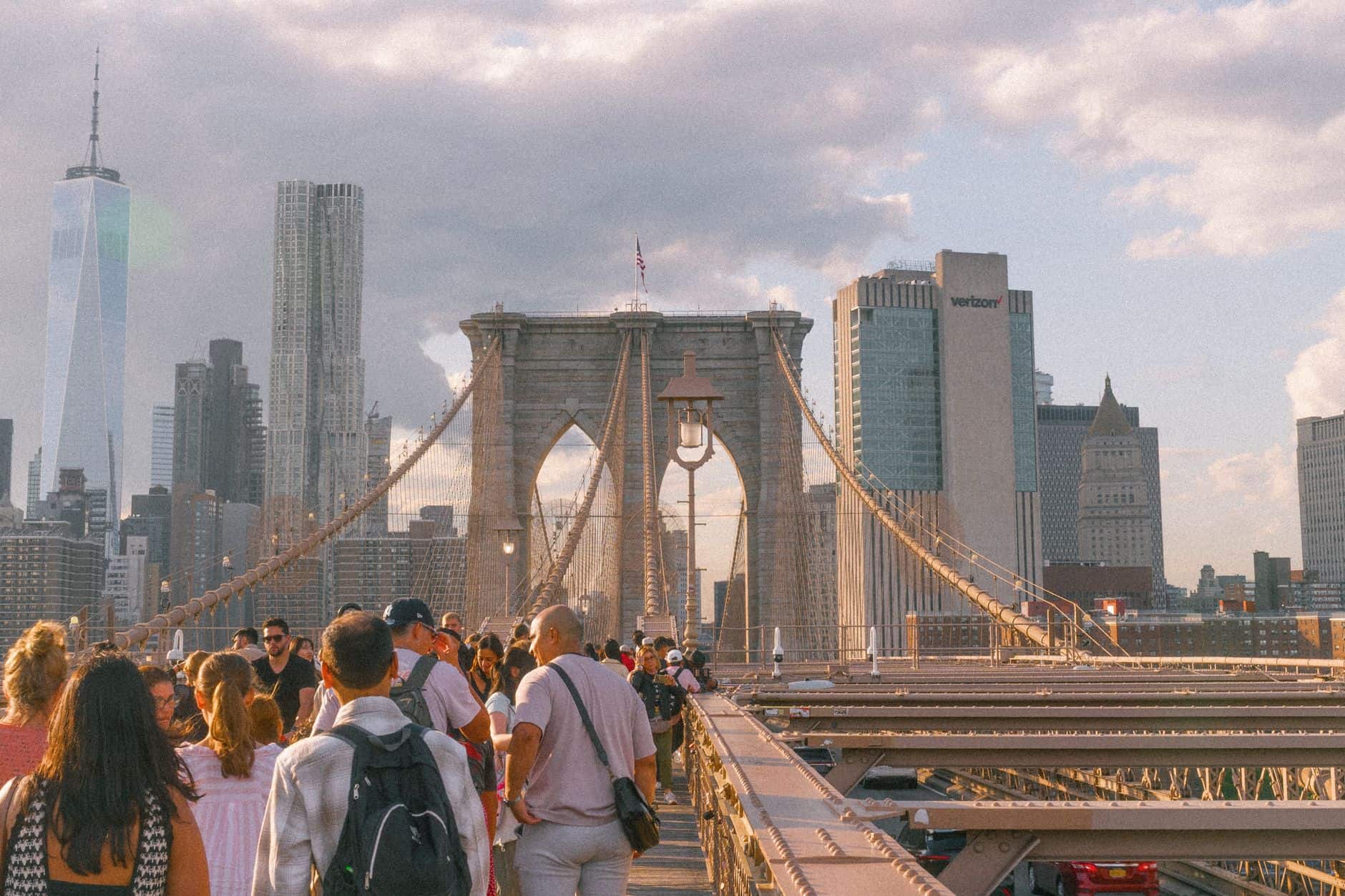 A vibrant sunset view of the Brooklyn Bridge with people enjoying the iconic skyline of New York City.