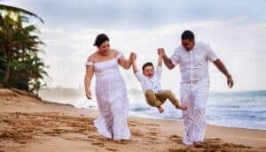 Smiling family in white clothing enjoys a fun day walking on the beach.