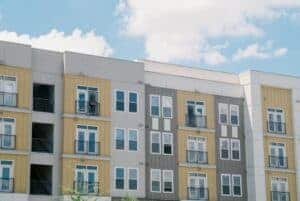 Contemporary apartment building exterior with yellow and grey panels under a clear blue sky.