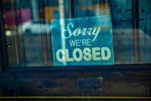Retro 'Sorry We're Closed' sign displayed on a rustic glass door, depicting temporary closure.