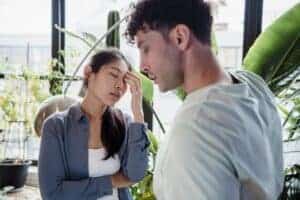 A couple experiencing a tense moment surrounded by plants in a modern space.