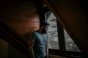 A thoughtful man stands by a window, lost in contemplation, indoors in Sri Lanka.