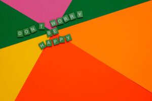 Colorful letter tiles spelling 'Don't Worry Be Happy' on vibrant paper background.