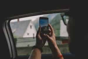Person takes photo of scenic view from car window with smartphone in Norway.