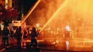 Firefighters in Valence spray water during a lively night festival, enhancing the drama of the scene.