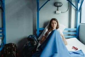 A young woman lies resting in a hospital bed, wrapped in a blue blanket, creating a calm and serene atmosphere.