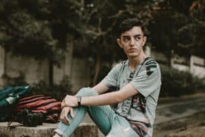 Casual young man sitting outdoors in São Paulo, with a camera beside him. Relaxed urban photography vibe.