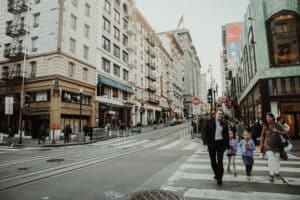 Vibrant city street with people crossing at a busy intersection on a lively day.