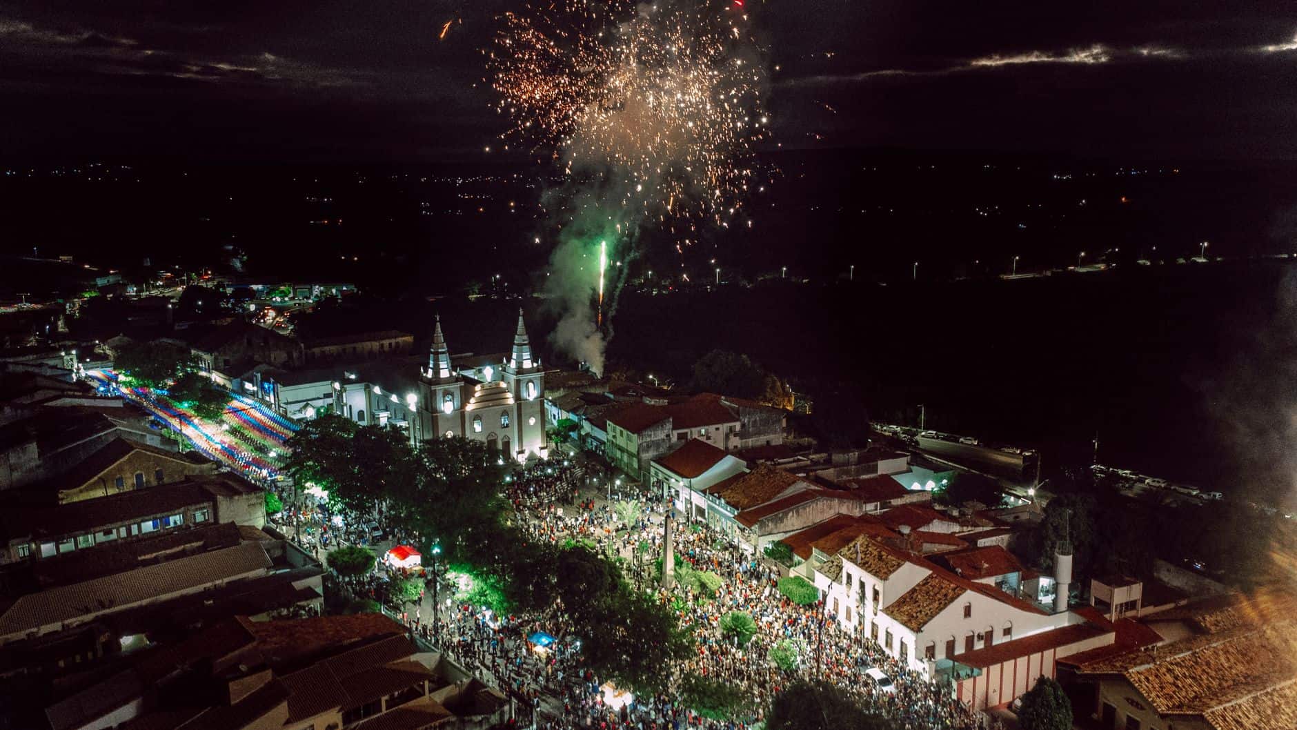 Vibrant aerial shot of a town with fireworks lighting up the night sky during a celebration or festival.