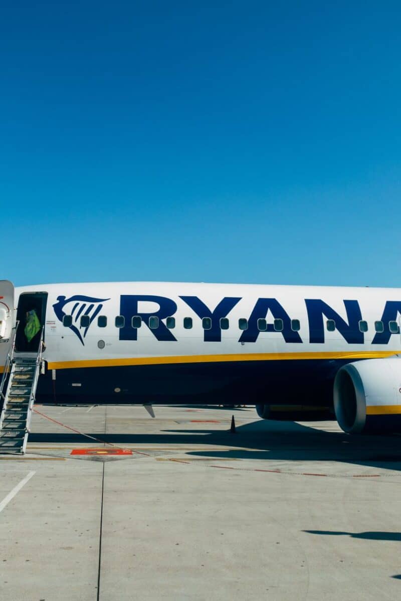 Ryanair airplane parked at airport, with clear blue sky and boarding ladder visible.