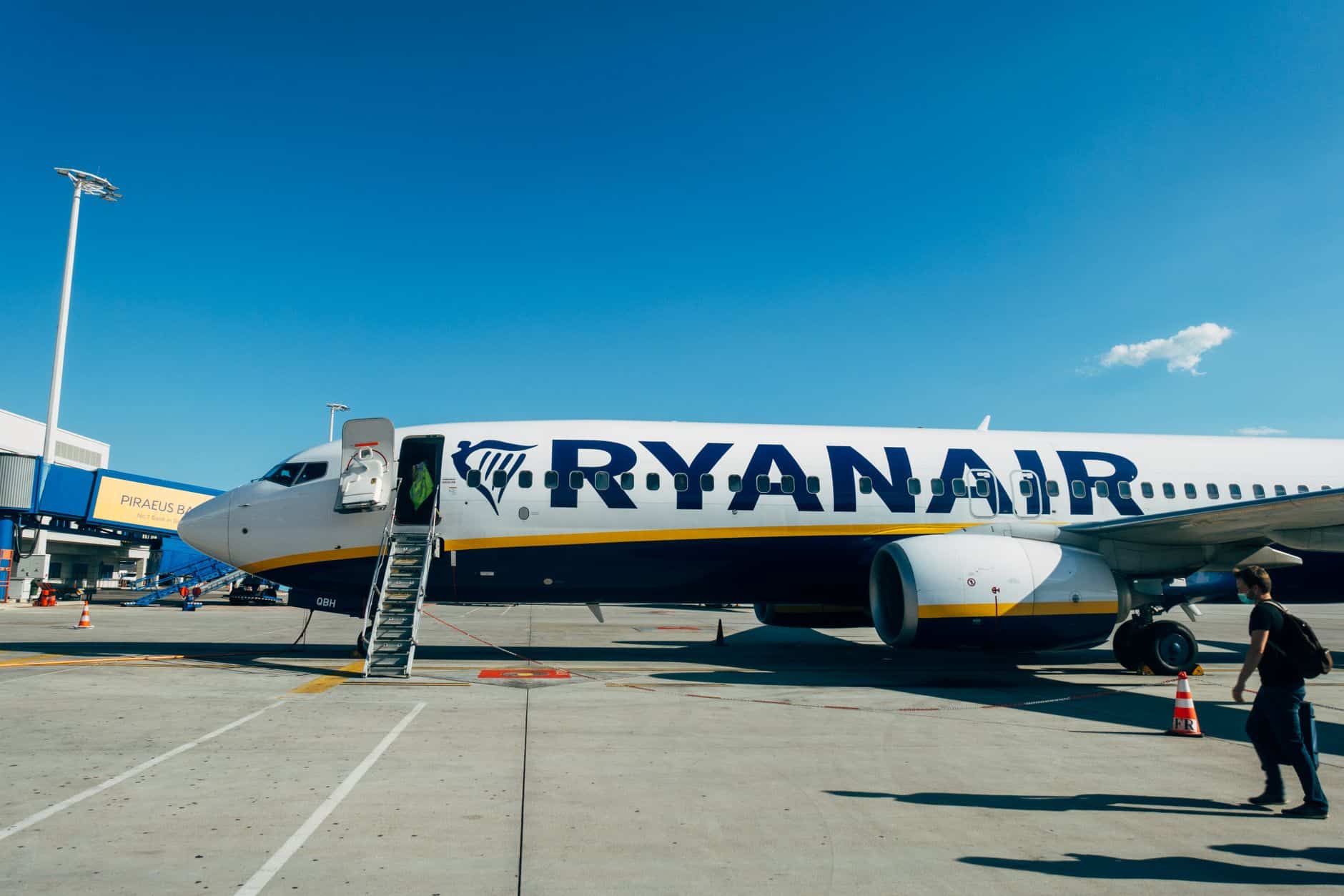 Ryanair airplane parked at airport, with clear blue sky and boarding ladder visible.