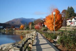 view of a walkway by the body of water and autumnal trees in a town