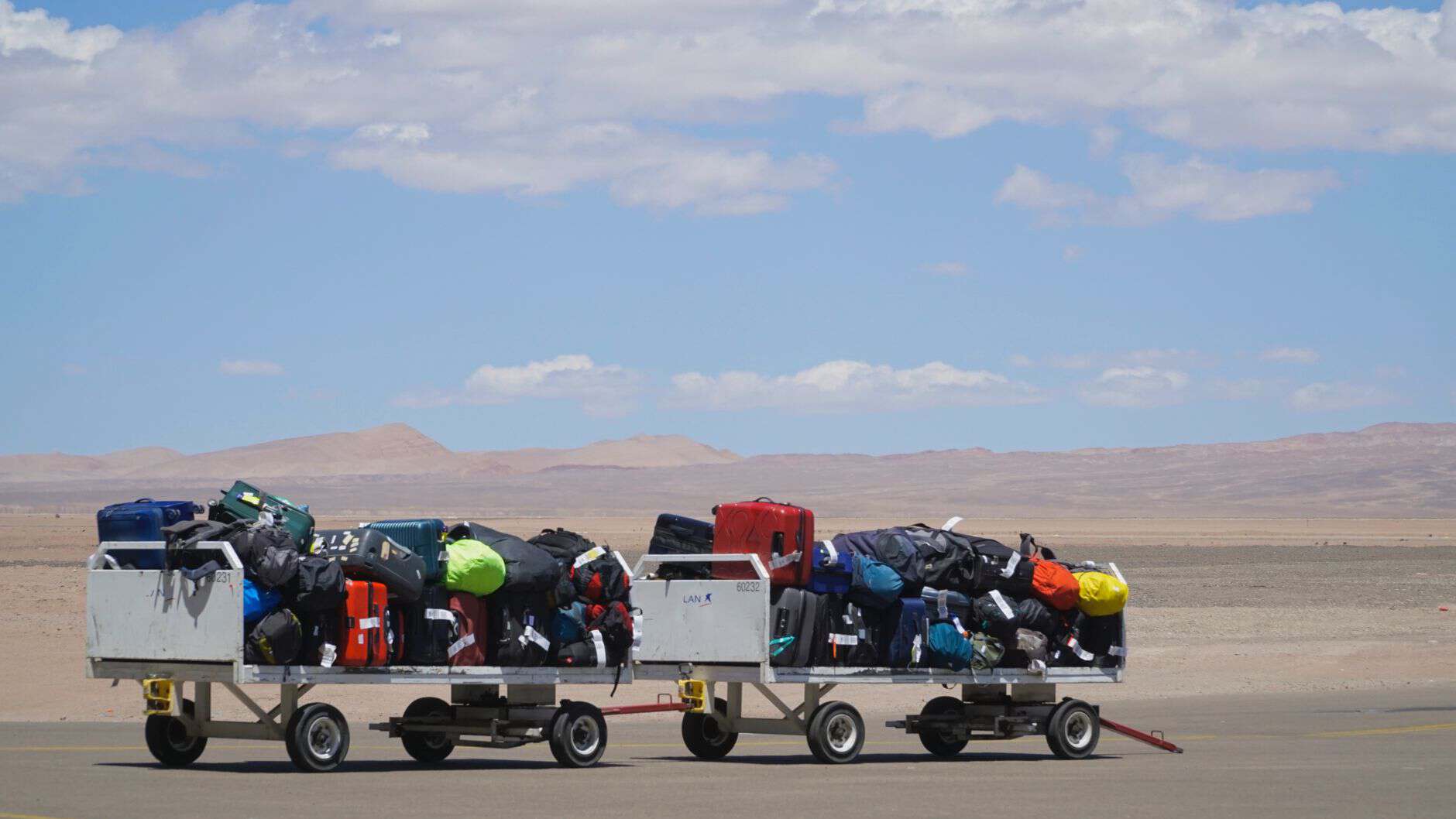 airport luggage carts loaded with colorful bags