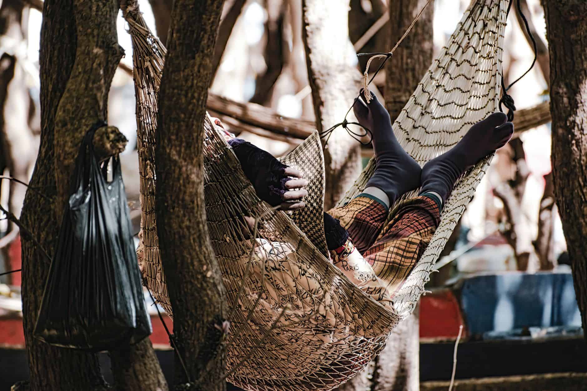 A person relaxes in a hammock among trees at Kampong Phluk, Cambodia. Perfect for travel and lifestyle themes.