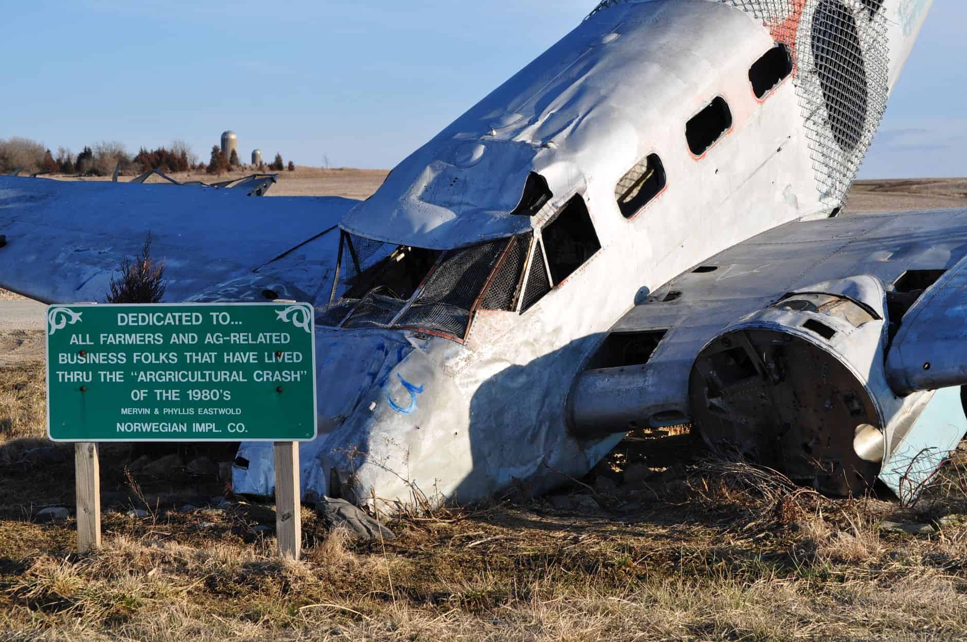A wrecked airplane amid an open farmland, symbolizing the agricultural crash of the 1980s.