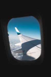View from an airplane window seat over clouds during flight