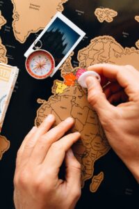 Person planning travel destinations with map and pinned photos
