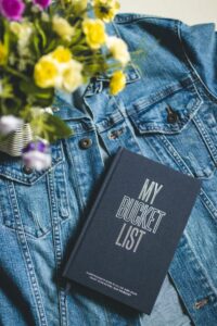 Person writing travel destinations in a bucket list journal