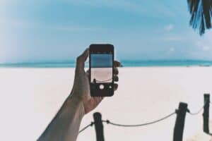 Person taking a smartphone photo at a scenic beach vacation spot