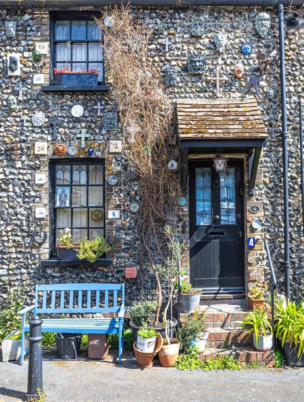 Rustic stone cottage with unique wall decor and garden bench in England.