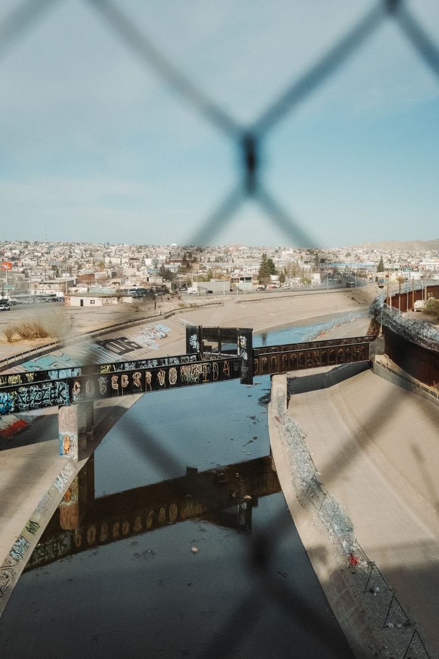 View of a graffiti-covered bridge spanning a river, showcasing El Paso's urban landscape.