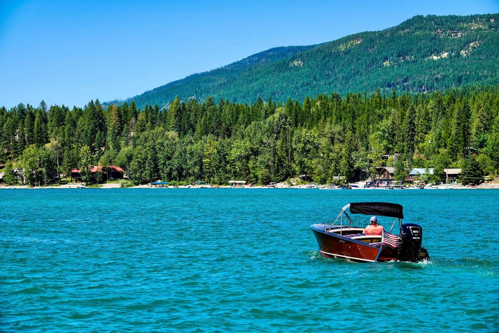 Enjoy leisure boating on serene Whitefish Lake with lush mountain views.
