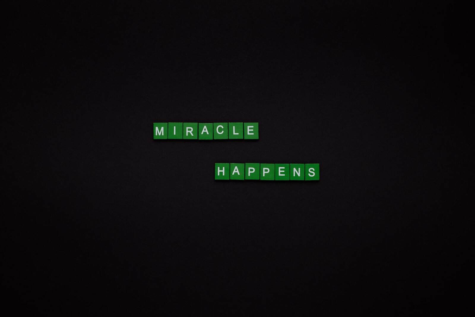 Motivational image featuring the words 'Miracle Happens' using green tiles on a black backdrop.