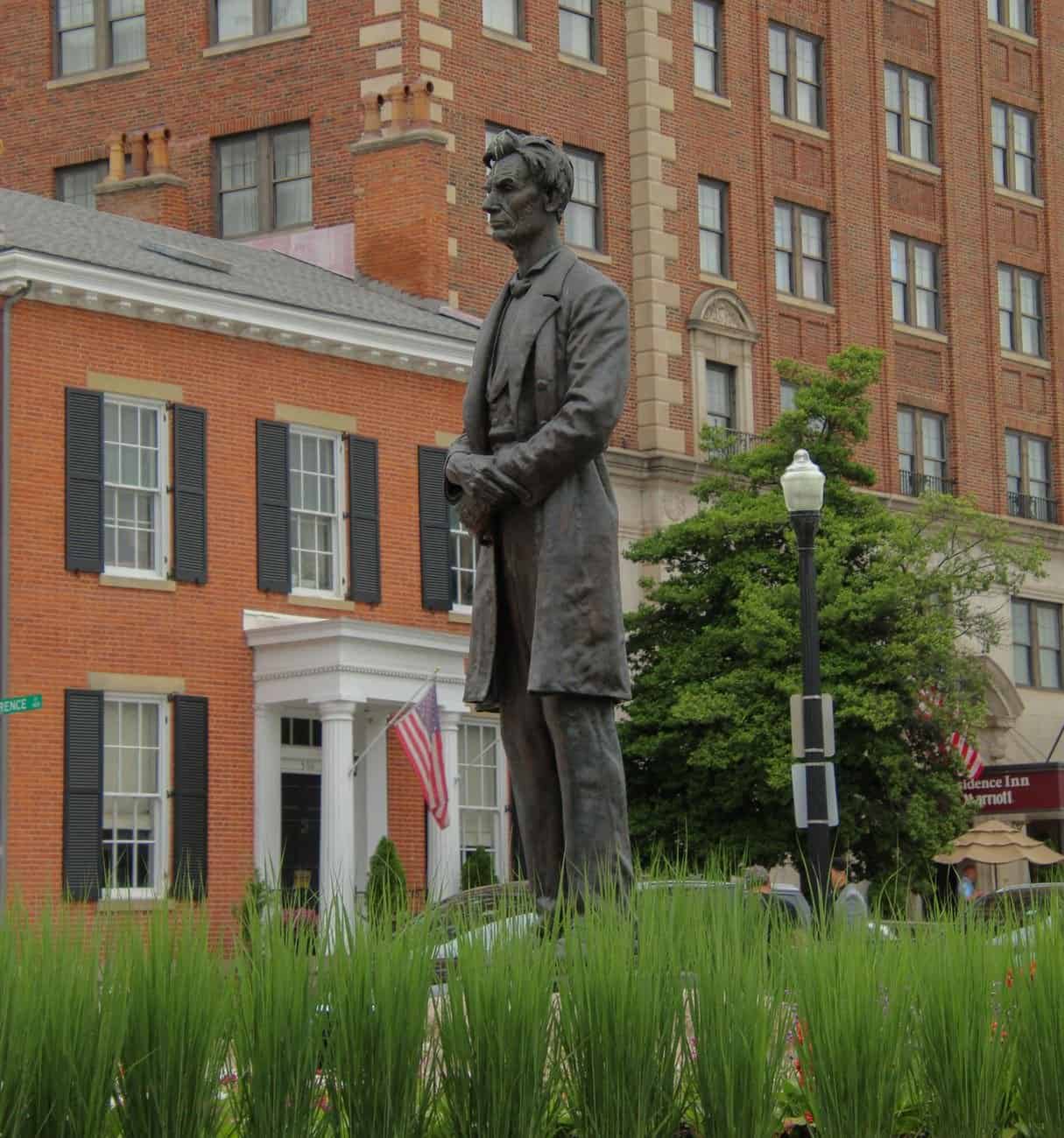 Bronze statue of Abraham Lincoln in front of historic building in a city environment.