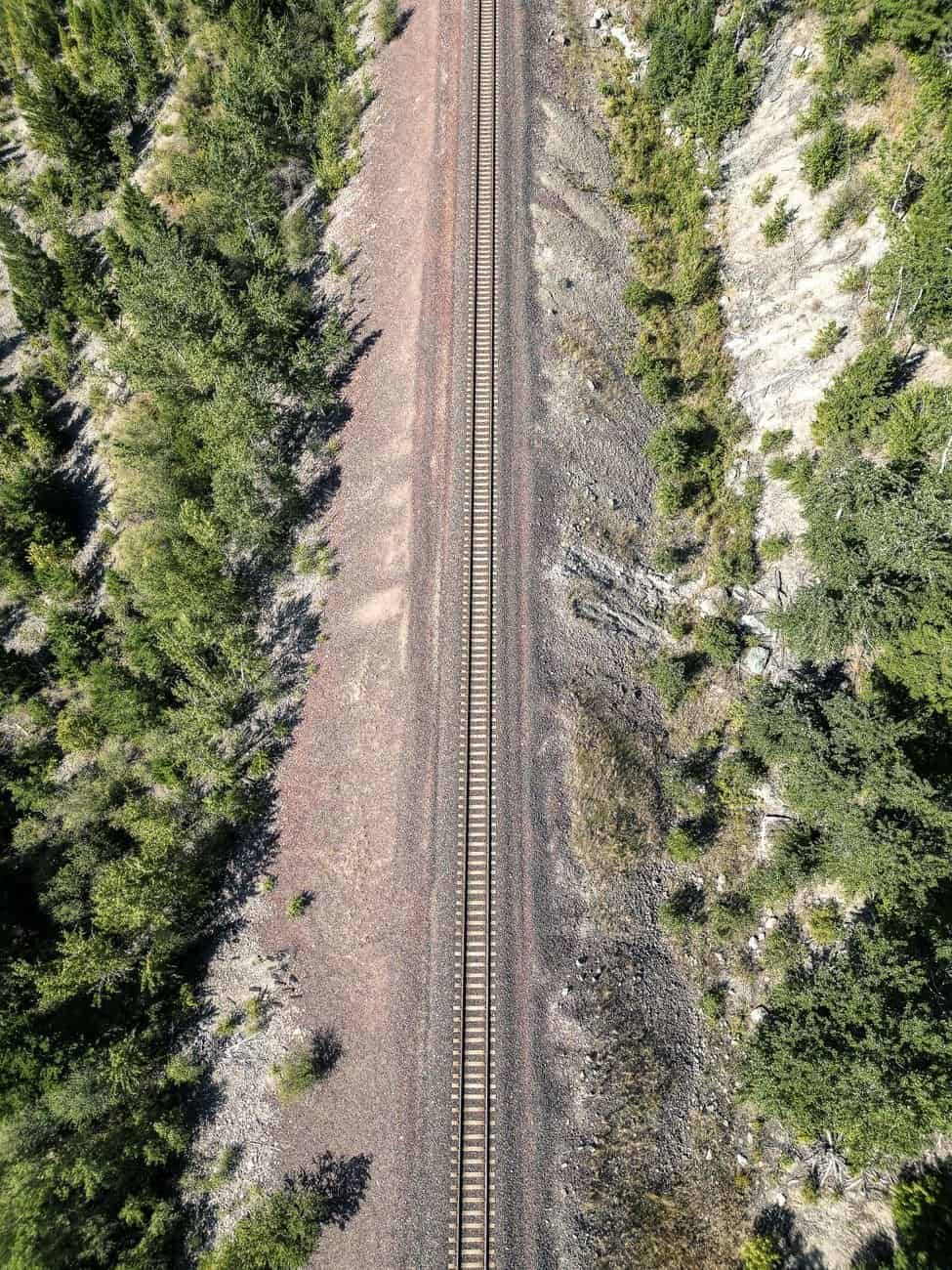 Captivating aerial shot of a railway cutting through lush forests in rural Montana, USA.