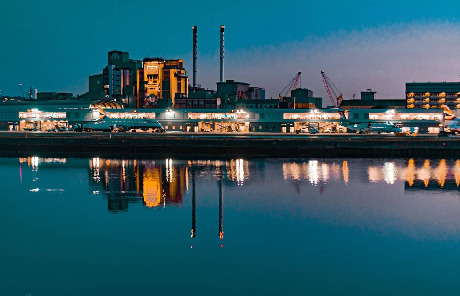 Illuminated skyline at night reflecting in the Thames near London City Airport.