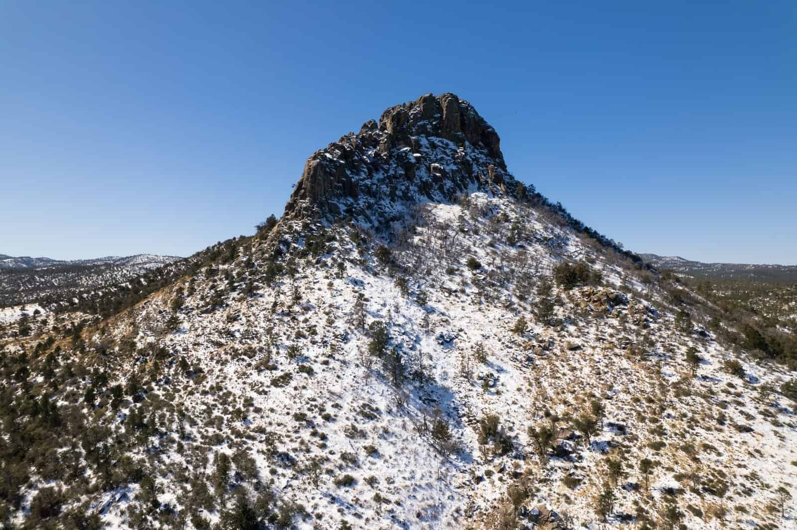 Aerial view of snowy Thumb Butte with a clear blue sky in Prescott, Arizona.