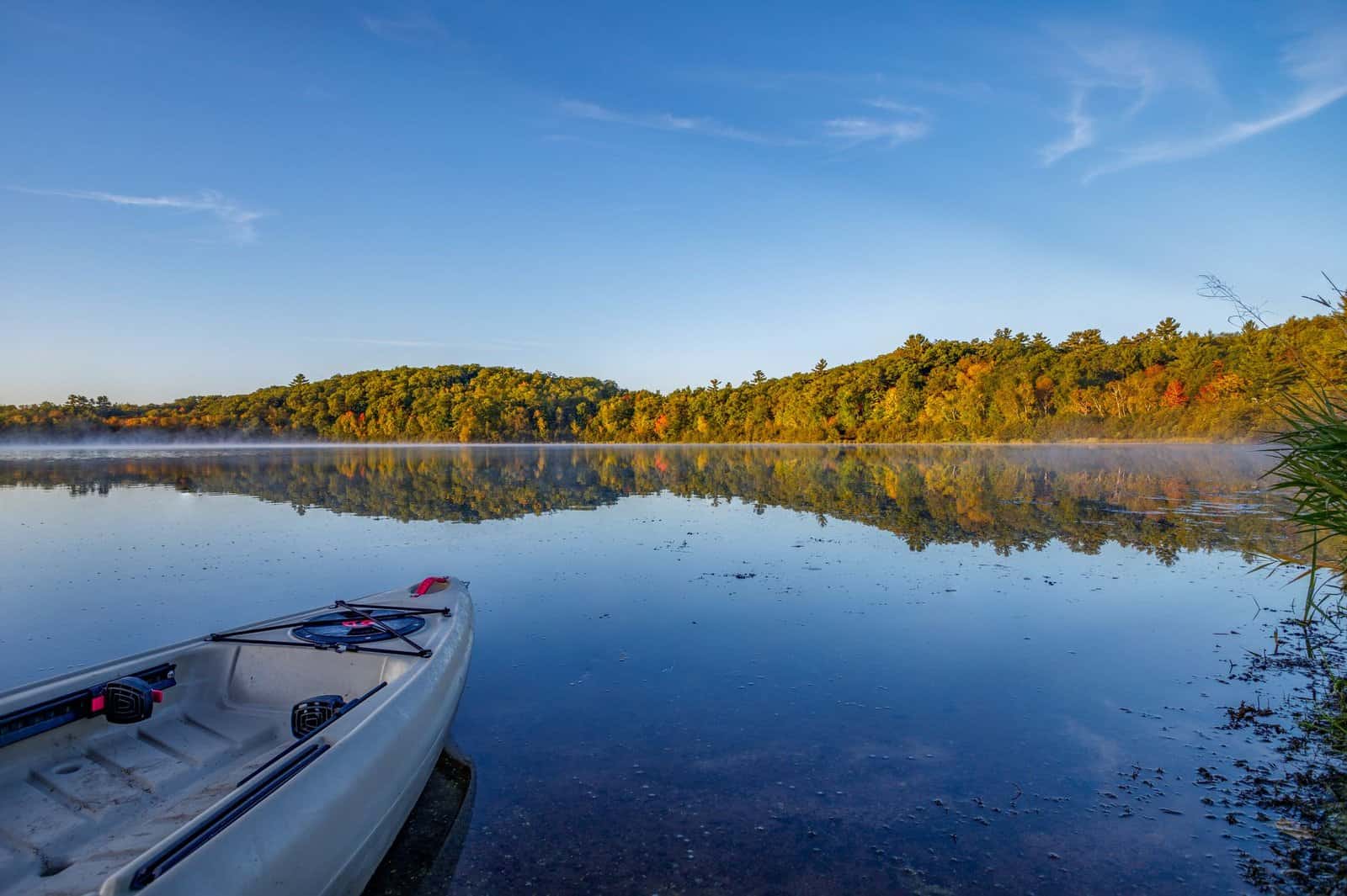 Beautiful autumn view of a lake in Wisconsin with a canoe, reflecting vibrant fall foliage.
