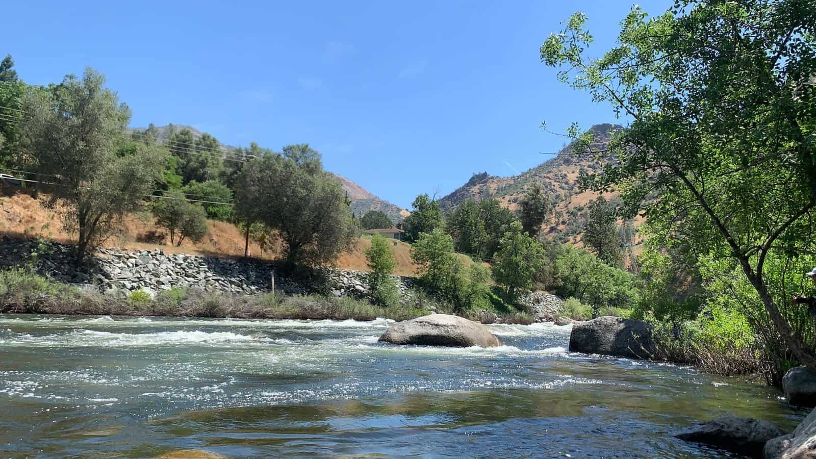 Tranquil view of the Merced River with trees and mountains in the backdrop, Yosemite National Park.