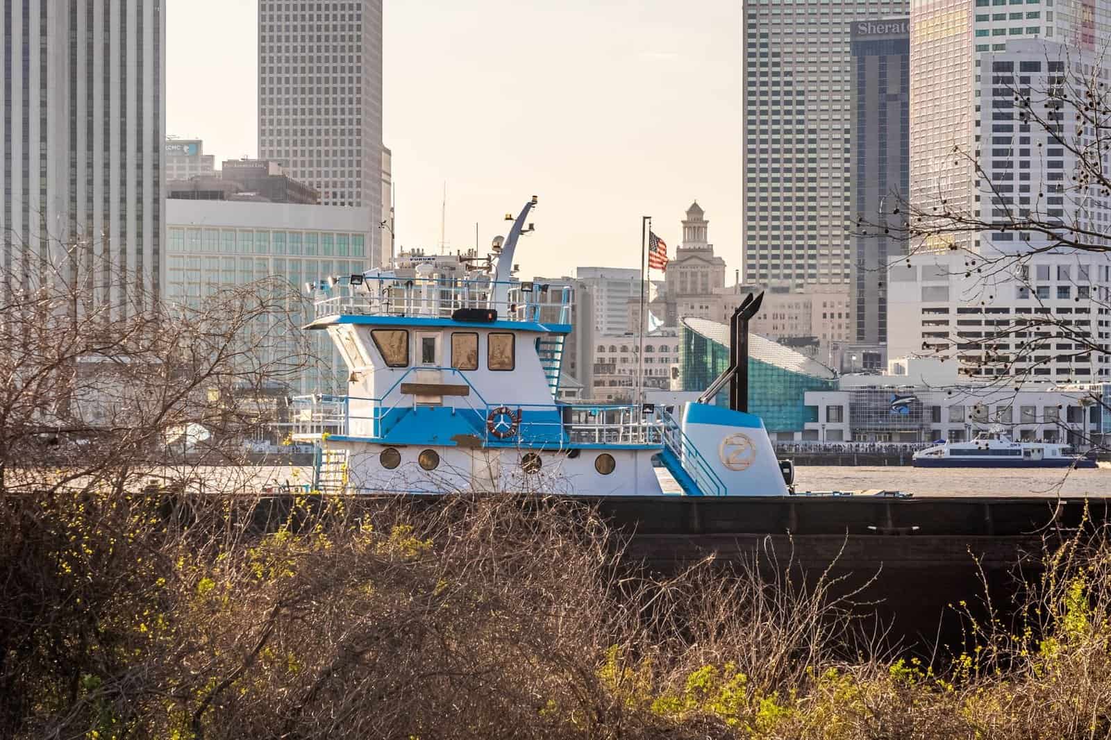 A tugboat on the Mississippi River with the iconic New Orleans skyline in the background.