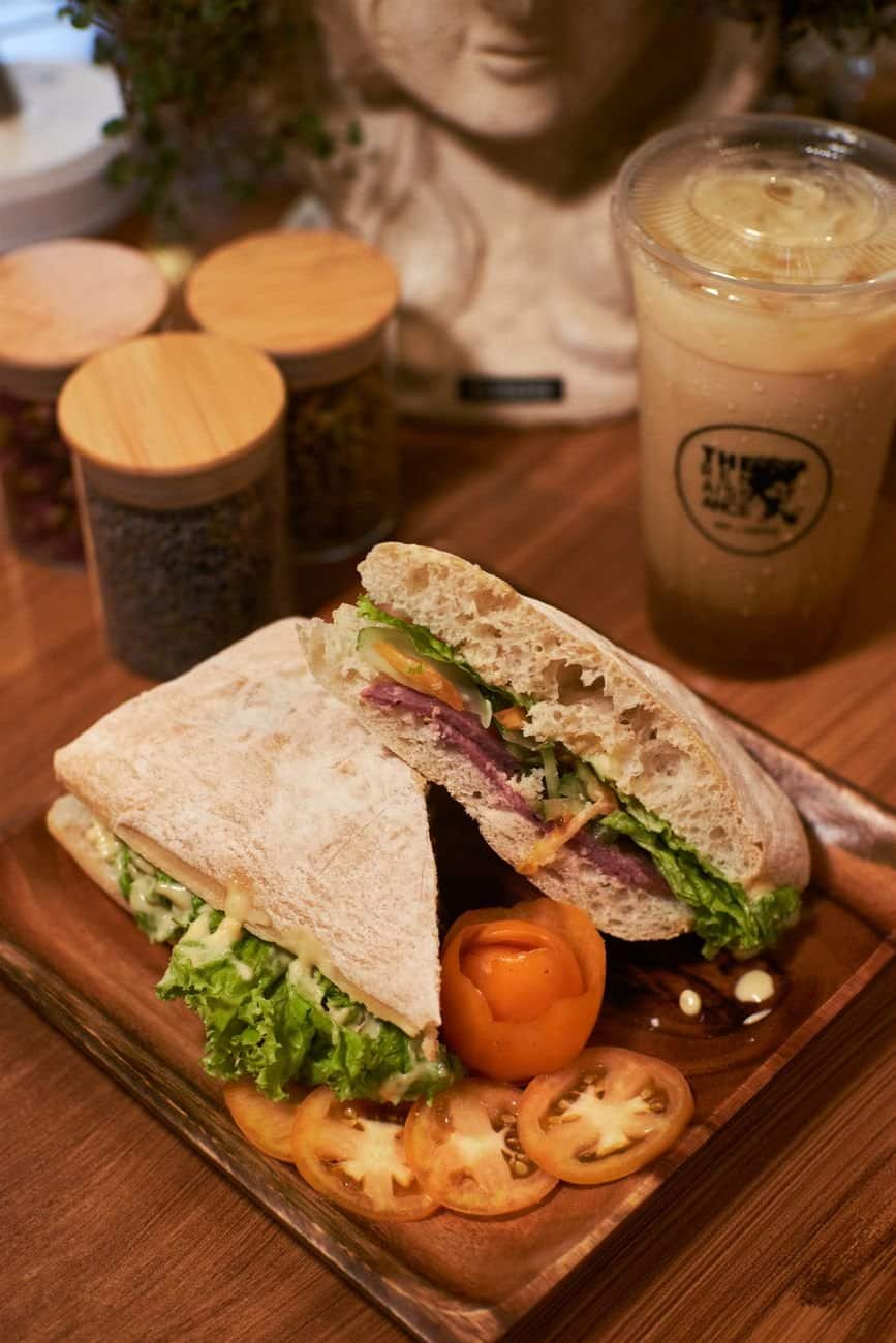 Close-up of tasty sandwich with fresh ingredients next to iced coffee.
