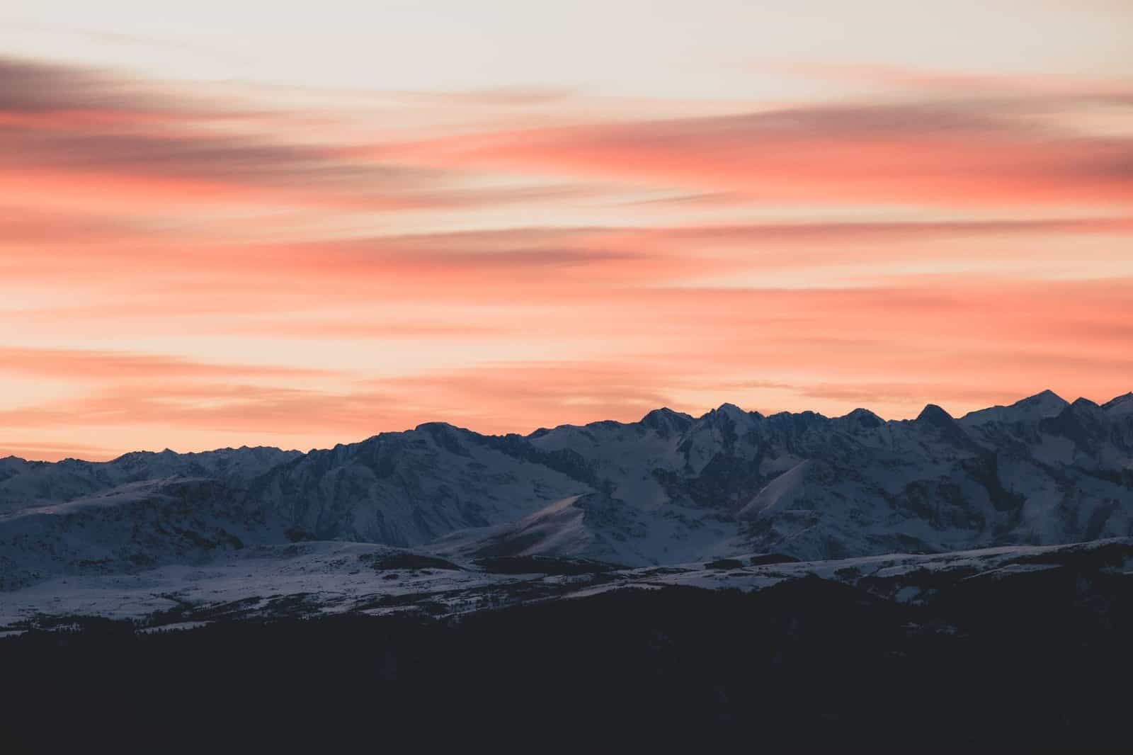 Stunning view of Trentino mountains with a vibrant sunset sky, showcasing winter's beauty.