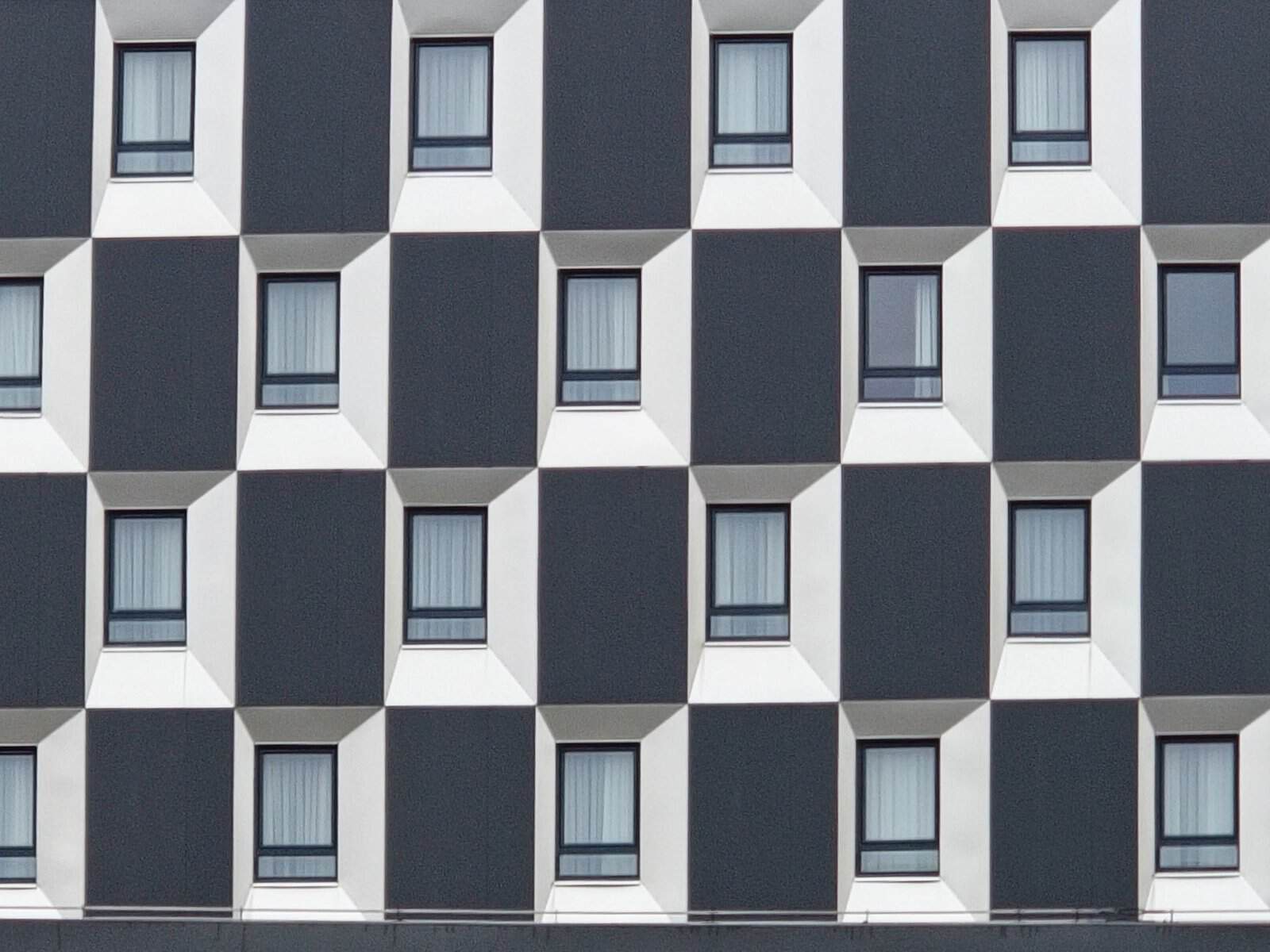Facade of a modern building with a repetitive geometric window pattern.