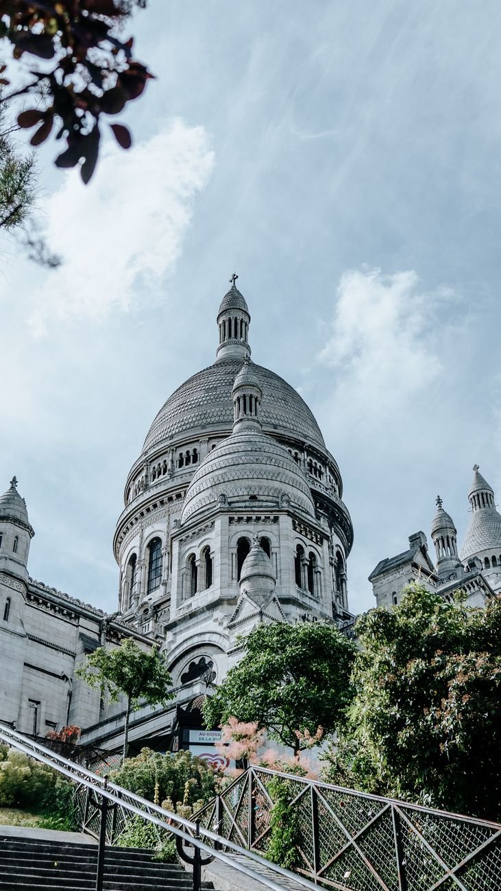 View of Sacré-Cœur Basilica in Paris with clear blue sky, showcasing its iconic architecture and lush surroundings.