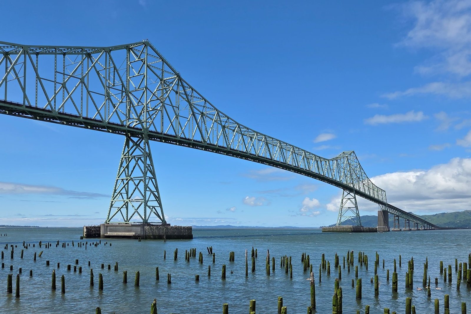 A scenic view of the Astoria-Megler Bridge over the Columbia River on a sunny day.
