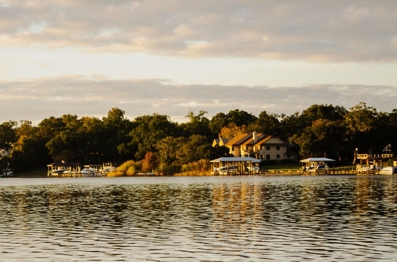 A serene lakeside view capturing golden hues of a resort surrounded by lush trees at sunset, perfect for vacationers.