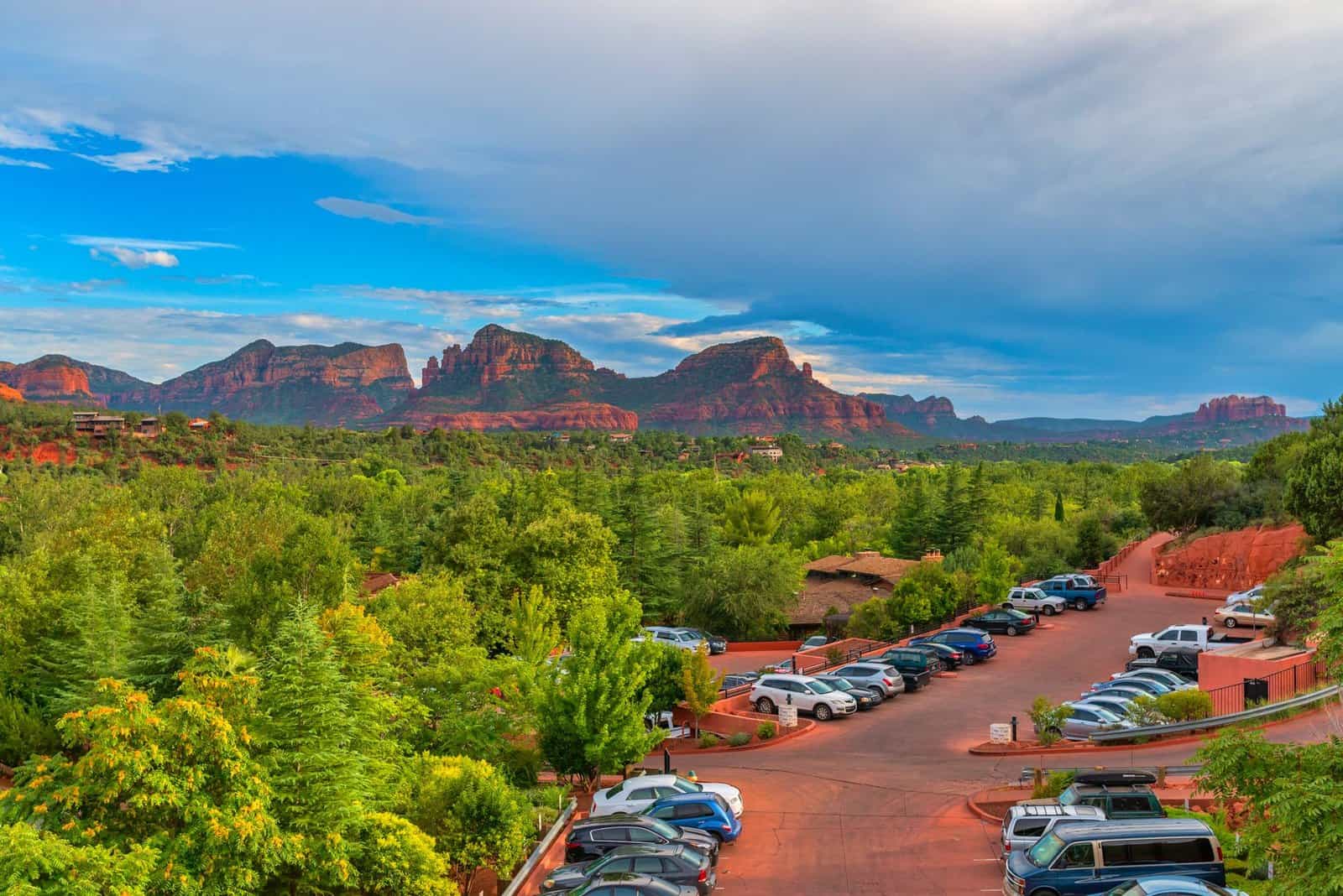 Breathtaking aerial view of Sedona, Arizona's red rock formations with lush greenery and parked cars.