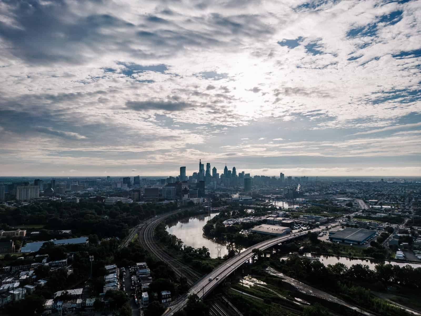 Stunning aerial view of Philadelphia's skyline featuring a river and cityscape under a cloud-filled sky.