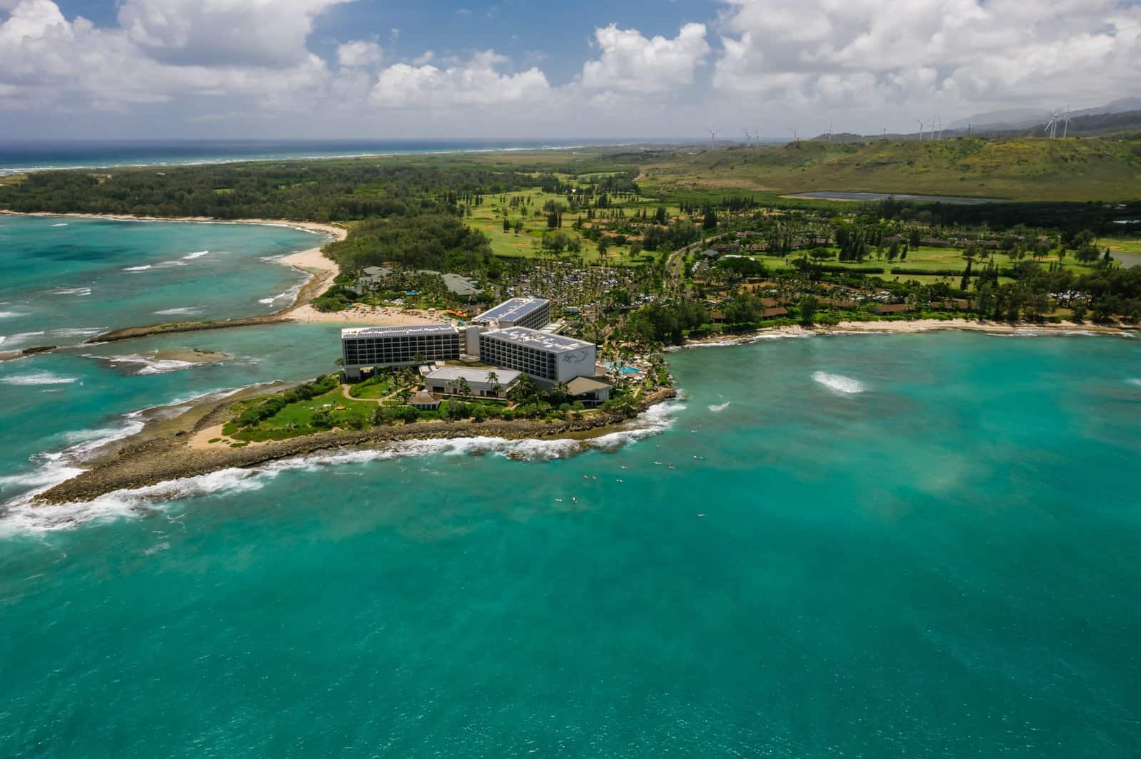 Stunning aerial view of a tropical island resort surrounded by turquoise waters and lush greenery.