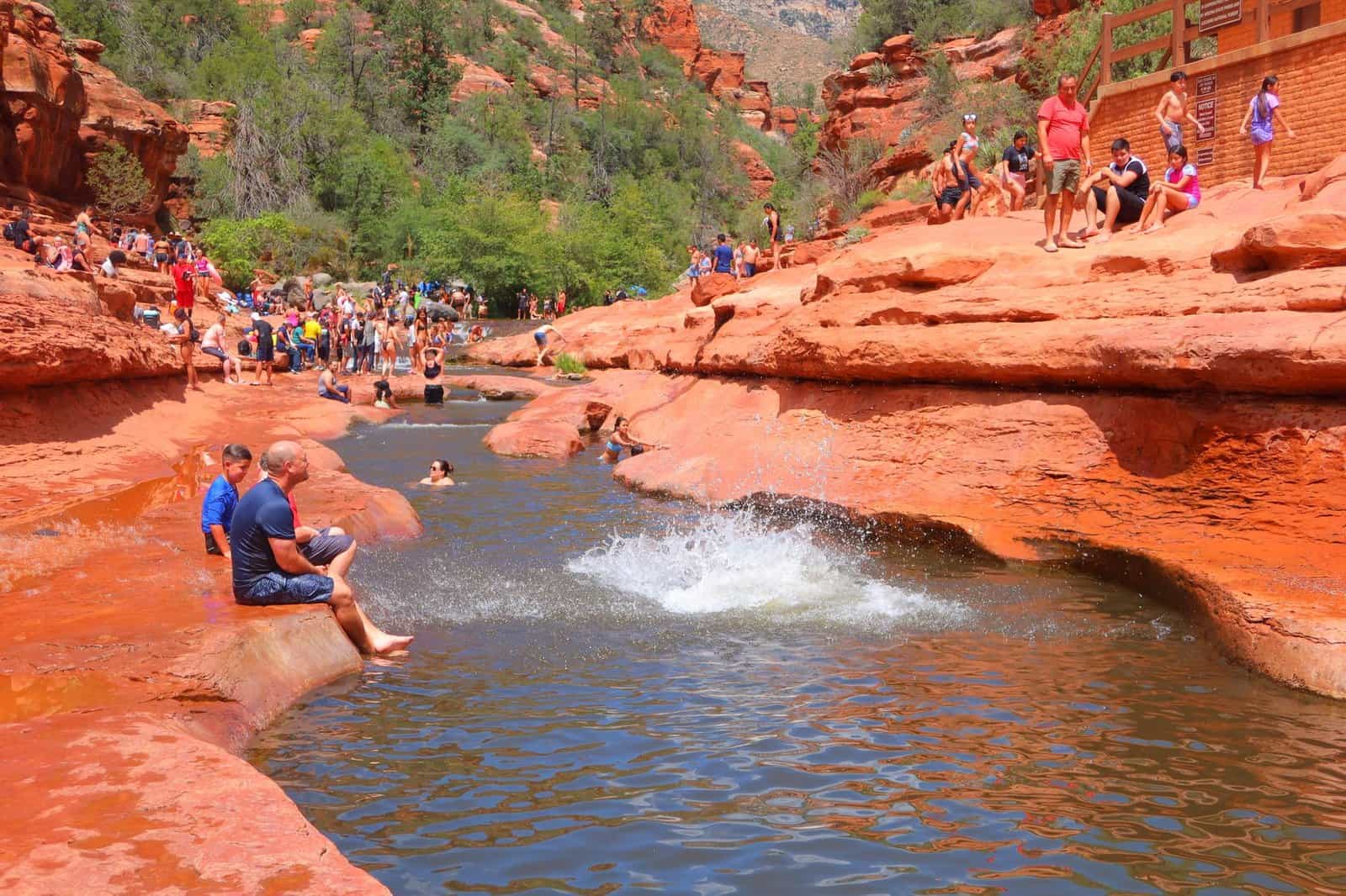 Visitors enjoying a sunny day at Slide Rock State Park in Arizona with swimming and sunbathing.